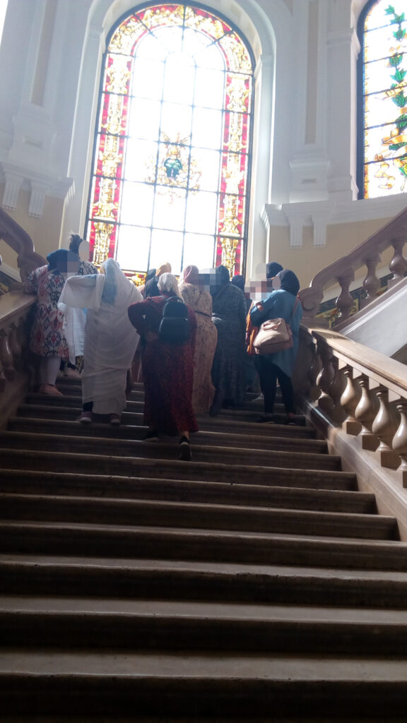 grupo de mujeres subiendo las escaleras de la facultad de derecho de la UVa, con una vidriera al fondo